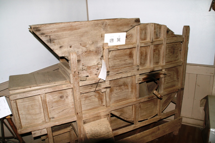 木製で脱穀機の様な形をし、中央付近に持ち手がついている唐箕の写真