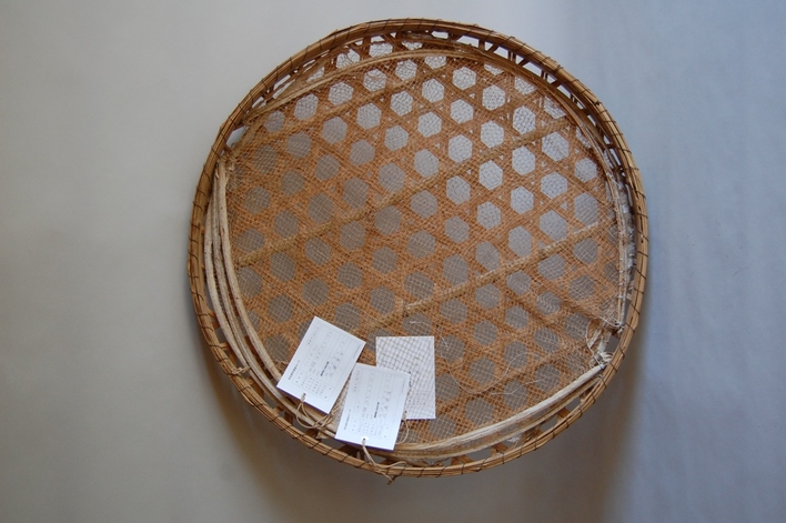 竹製で網目状に編まれた丸い竹ざるのかごわらだの写真