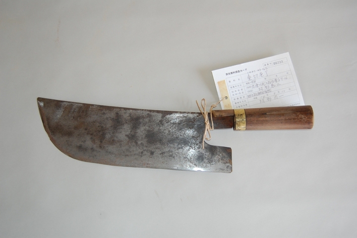 木の持ち手と、幅が広くて平らな鉄の刃がついた桑切包丁の写真