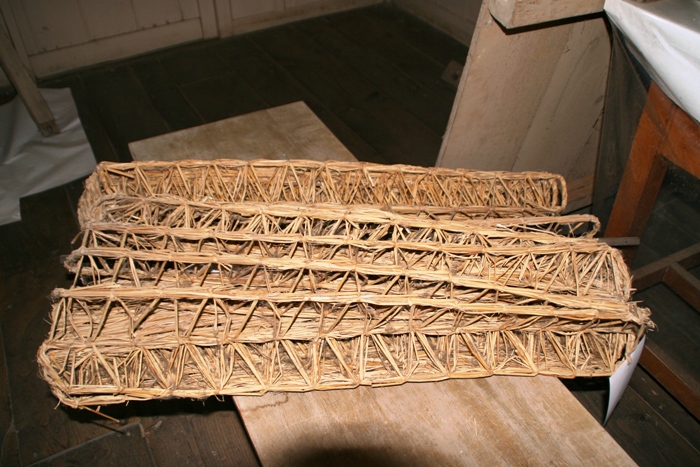 長方形で中が空洞の、わらを編んで作られた細長い筒状の養蚕道具の「あみ」の写真