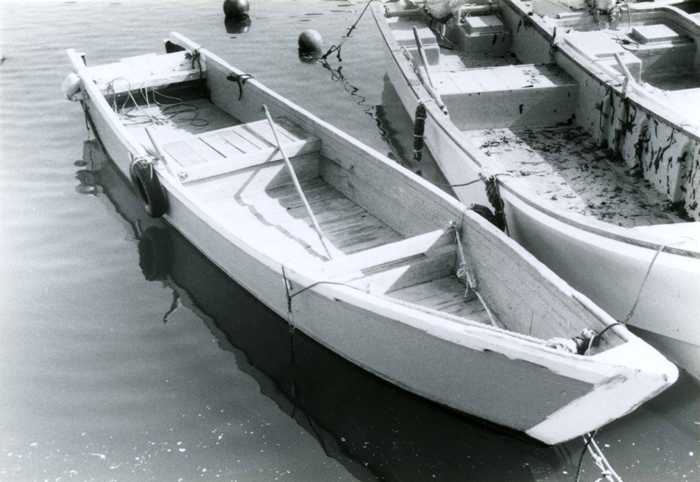 板材を継ぎ合せて作った手漕ぎ船オッタテサッパが港に浮かんでいる白黒写真