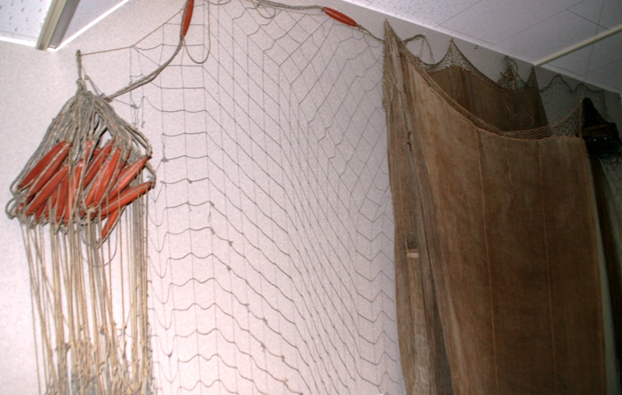 細い糸で編まれた漁網が壁に掛けられ並んでいる刺し網の写真