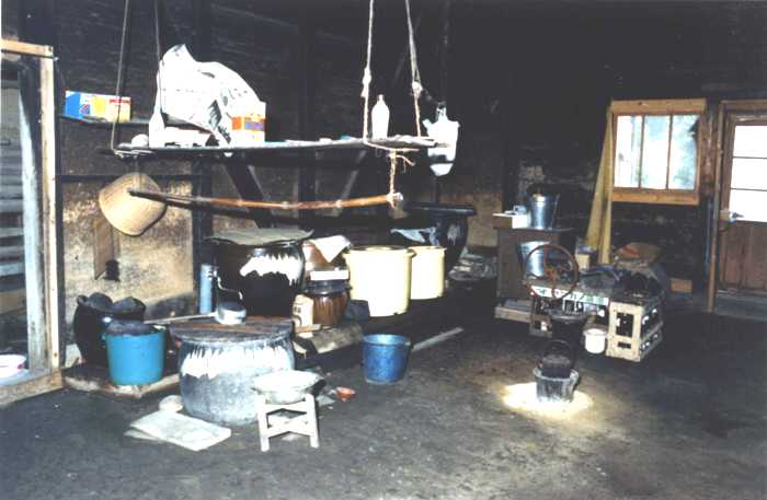 土間に囲炉裏やバケツ、調理器具などが所狭しと置かれた昔の調理や作業スペース「にわ」の写真
