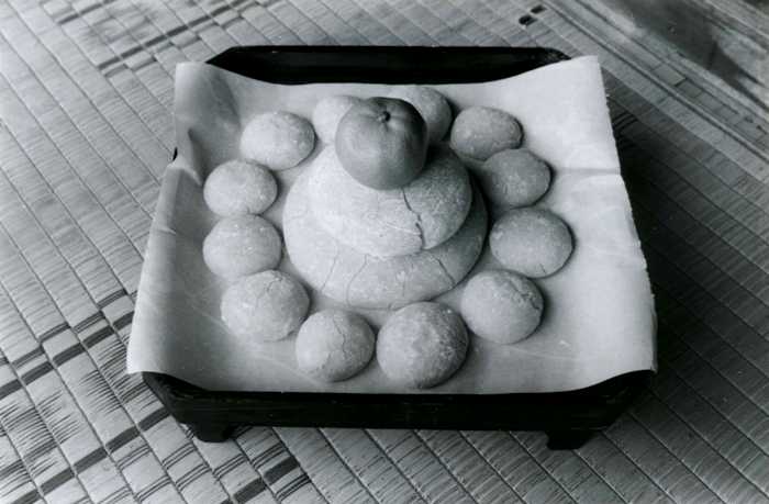 折敷に紙を敷き、その上に大小二段に重ねられた鏡餅と橙、さらに周囲に小さな餅が12個並べられている「十二のおそなえ」を写した白黒写真