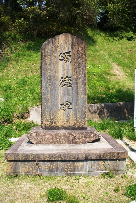 草地の中に石の台座の上へ直立する大きな石碑があり、正面に「頌徳碑」と大きく縦書きで刻まれている頌徳碑の写真