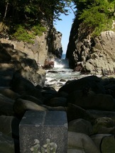 両側を切り立った岩壁に挟まれた狭い割れ目から海水が打ち寄せている神割崎の写真