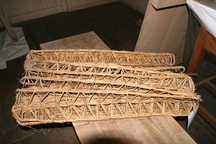 長方形で中が空洞の、わらを編んで作られた細長い筒状の養蚕道具の「あみ」の写真