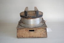 木製の蓋の上に取っ手が付いた、木製の台座と金属製の大きな鍋がセットになっている炊飯道具「羽釜」の写真