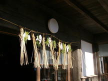 古民家の玄関上部に、しめ縄が張られ松や紙垂が飾られて正月の神聖な空気を表している写真