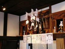 家屋の梁の上にしめ縄や紙垂、切り紙の飾りが華やかに吊るされた神棚の正月飾りを写した写真