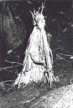 藁や枝を使って三角錐状に組まれた小さな祈祷用の構造物つとこが地面に立てられている様子が写っている白黒写真