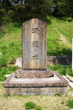 草地の中に石の台座の上へ直立する大きな石碑があり、正面に「頌徳碑」と大きく縦書きで刻まれている頌徳碑の写真