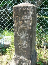 金網の前に立つ四角柱の石碑で、縦書きの文字が刻まれているが風化しており、一部が読み取りにくくなっている昭和八年津波境碑の写真