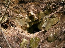 崩れた岩の間に黒くぽっかりと開いた穴があり、坑道の入口が見えている坑口2/十枚山産金跡の写真
