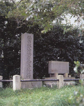 草地に立つ碑文が刻まれた石碑の写真