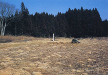 白色の標柱のそばに乾いた草地が広がっている長者屋敷遺跡の写真