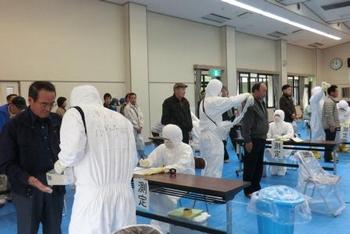 白い全身防護服を着た人が訪れた市民の方の検査を行っている写真