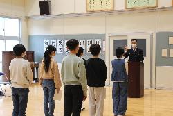 消防クラブ修了式で消防署の方の話を聞く児童の様子