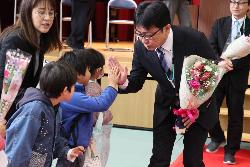 離任式後、花道を歩きながら児童と最後の別れをする職員の様子