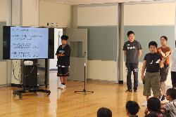 児童朝会で計画委員会の活動の中身をクイズ形式で紹介する児童の様子
