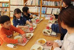 机を囲んで親子で一緒に給食を食べる子供たちの様子