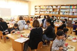 机を囲んで親子で一緒に給食を食べる子供たちの様子