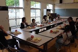 机を並べてお家の人と一緒に給食を食べる子供たちの様子