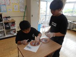 児童が自分で選んだ素材をチャームの土台にレイアウトしている様子