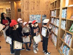 たくさんの本の量にびっくりしながらも職員からの説明を聞いている子供たちの様子