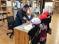 本の貸し出しの方法について職員から説明を受けている子供たちの様子