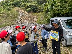 何でもない石ころが実は化石だったと説明を受ける子供たち