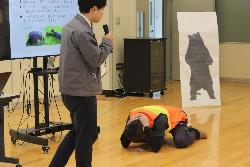 クマに襲われそうになったときの身の守り方について実演する町の職員の様子