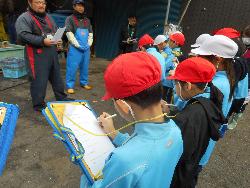 ホタテ養殖の仕事について説明を受けながら熱心にメモをとる子供たちの様子