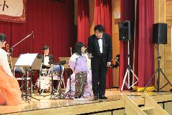 指揮者体験に名乗り出た子供にクラリネット奏者がステージ上でインタビューをする様子