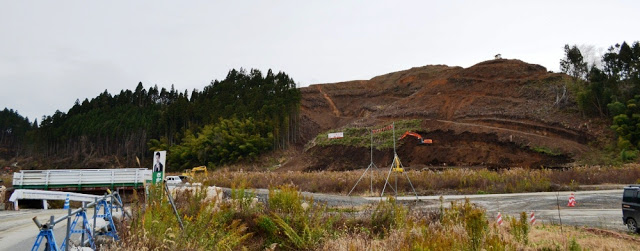 数台のショベルカーが稼働しており、山肌が大きく削られている造成地で工事が行われている現場の写真