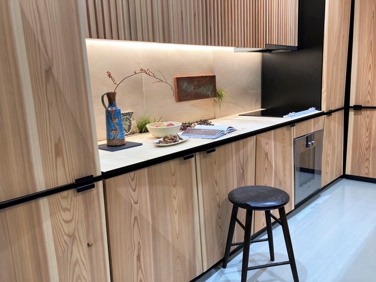 木目のキッチンカウンター上に青い花瓶や器、開いた本が置かれ、落ち着いた照明が当たる様子の写真