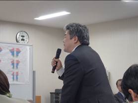 席から立ちあがり、マイクを持って話をしている出席者の男性の写真