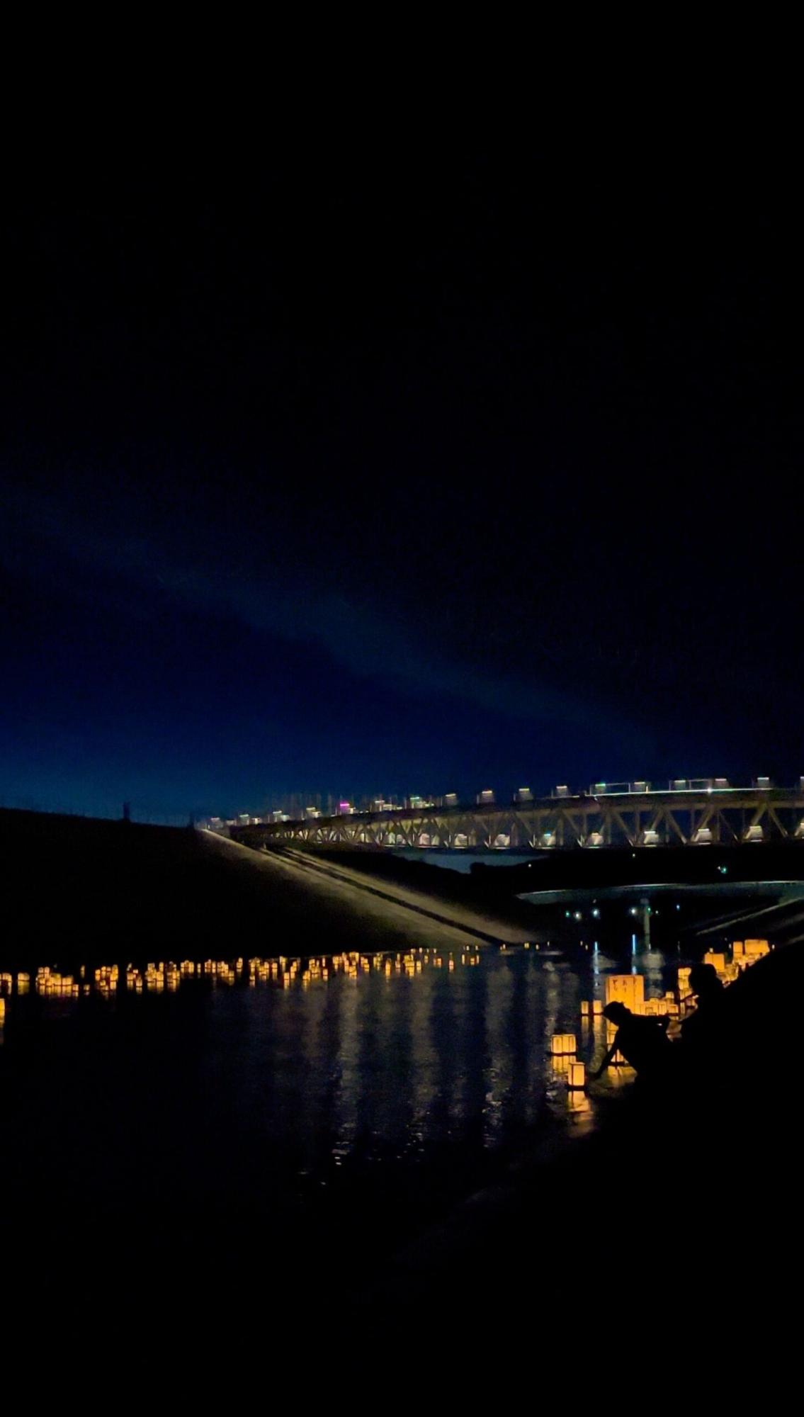夜の川にたくさんの灯篭が浮かんでいる様子を撮影した写真