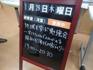 1月28日木曜日「「地域を学ぶ勉強会」8ミリフィルムでよみがえる昭和40年代の家づくり」と書かれた会議室の立て看板の写真