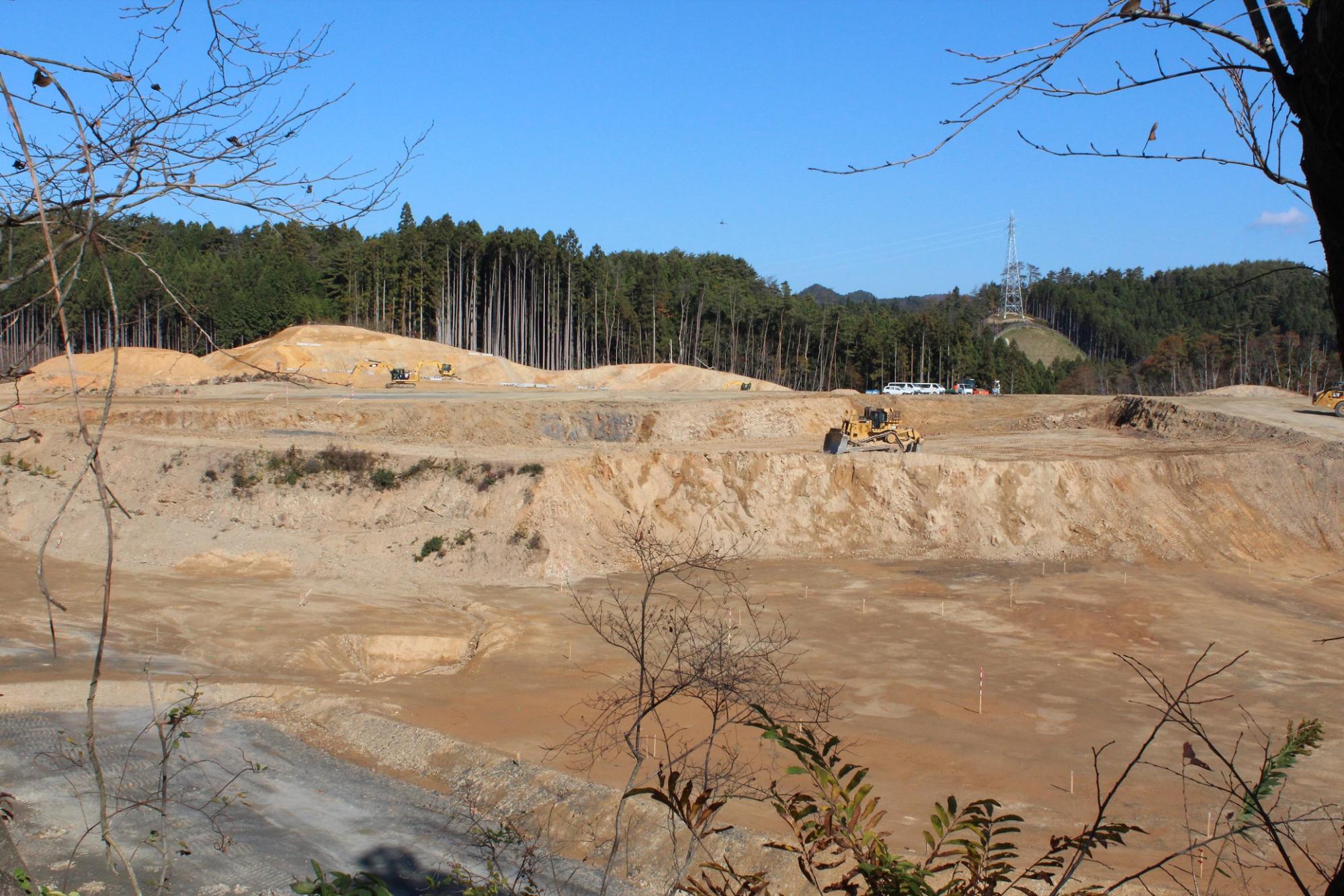 起伏のある造成地に重機が点在している写真