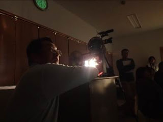 カーテンを閉め、照明を消して暗くした室内で、映写機のからの光が煌々としている様子の写真