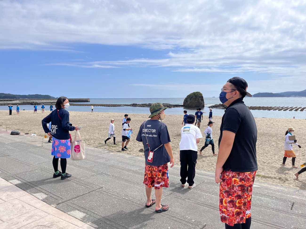 ビーチでアルティメットの試合を観戦する人々や、スタッフとして動く人々の写真