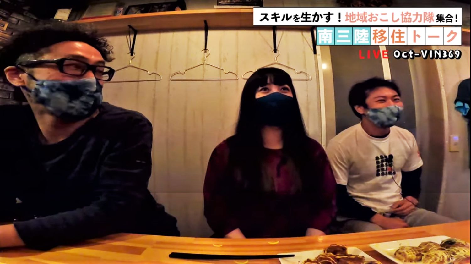 YouTubeでライブ配信された南三陸移住トークイベントで、地域おこし協力隊の3人が笑顔で並んで座り、会話を楽しみながらタコ焼きが並んだカウンターで話を聞いている様子の写真