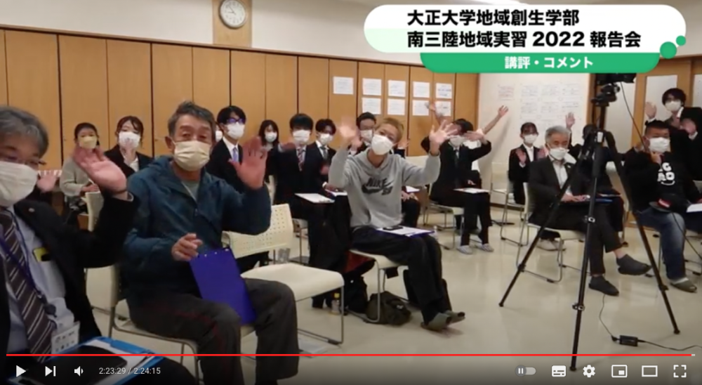 会議室に集まった大学生や地域の人々がカメラに向かって手を振っており、画面上部には「南三陸地域実習2022報告会」と書かれたテロップが表示された報告会動画の再生中画面をスクリーンショットした写真