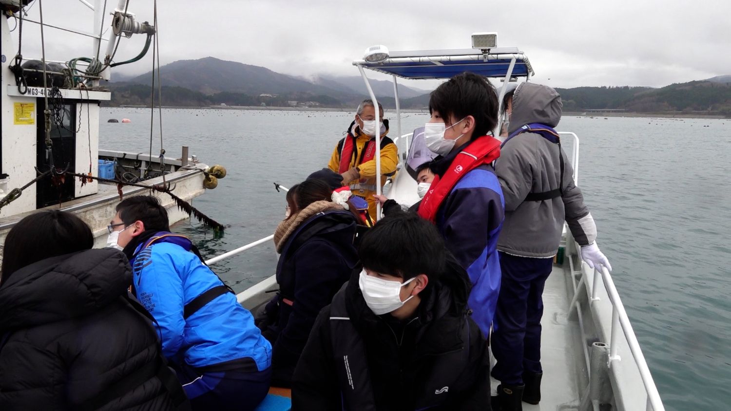 となりの船に乗った生徒たちが、ワインの海中熟成の作業を見学する様子の写真