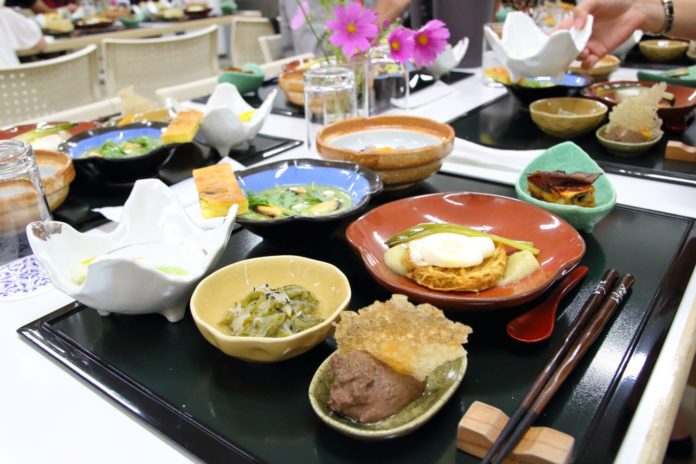 小鉢やお皿に料理が美しく盛り付けられたお盆がテーブルに並んでいる写真