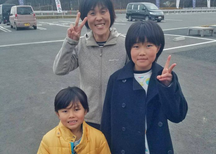 駐車場で2人の娘さんと阿部純子さんが並んで笑顔で写っている写真