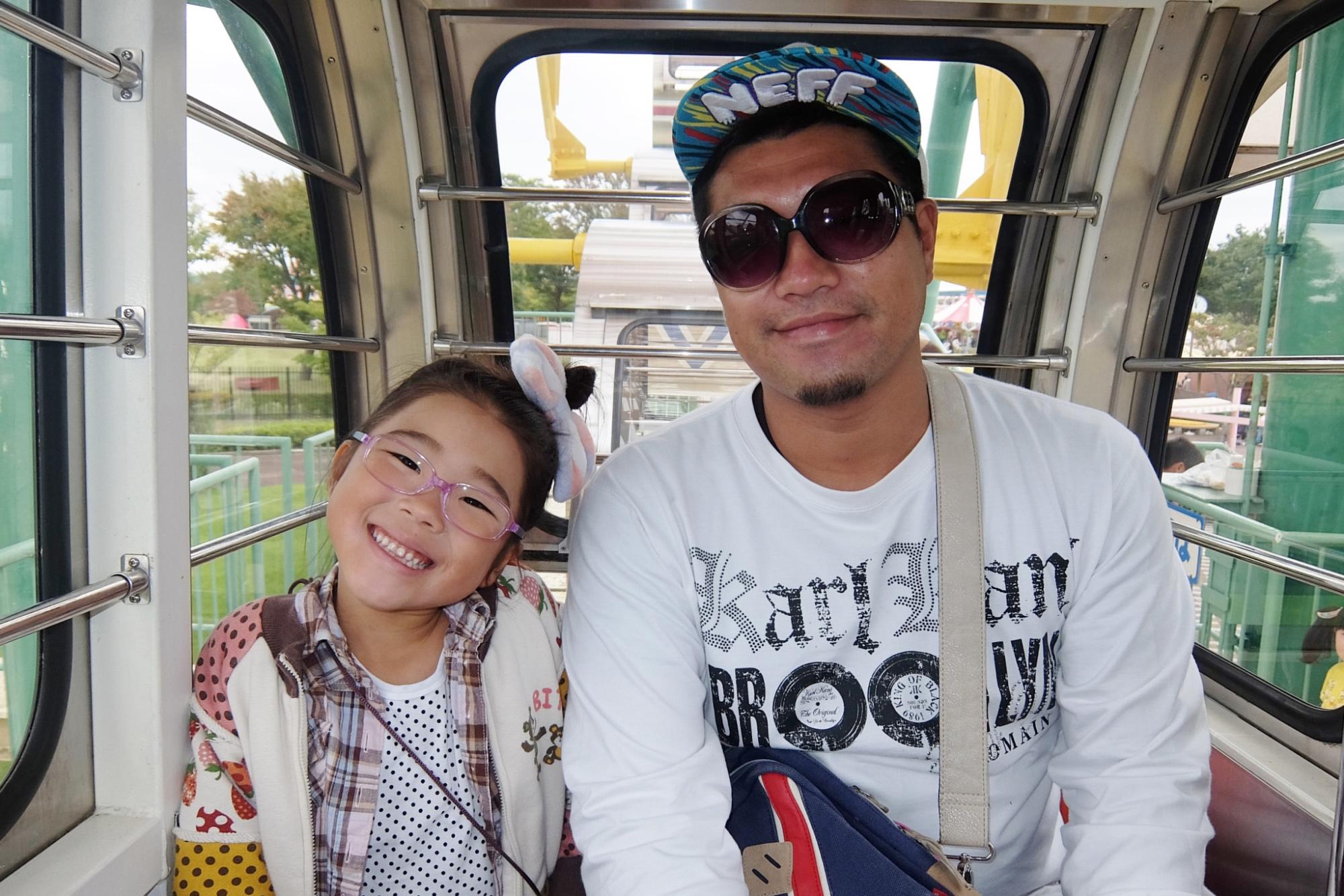 観覧車のゴンドラ内で帽子とサングラスをかけた工藤大樹さんと光奈乃ちゃんが並び、笑顔を見せる写真