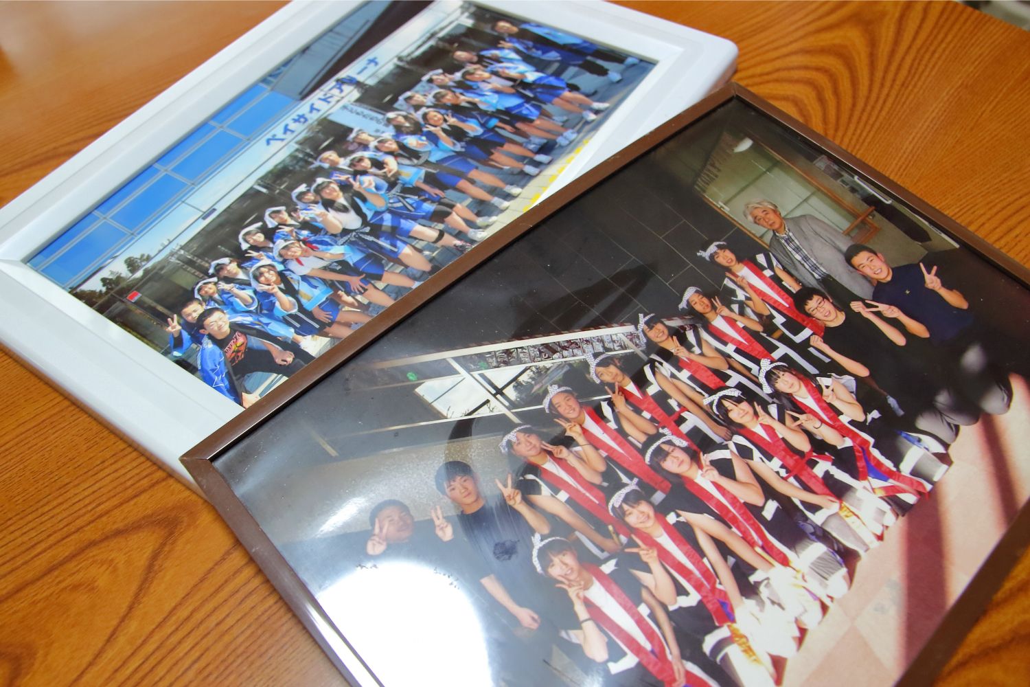 木の机の上に、法被姿の子どもたちが並んで写っている2枚の集合写真が白と茶色の額に入れて飾られている写真