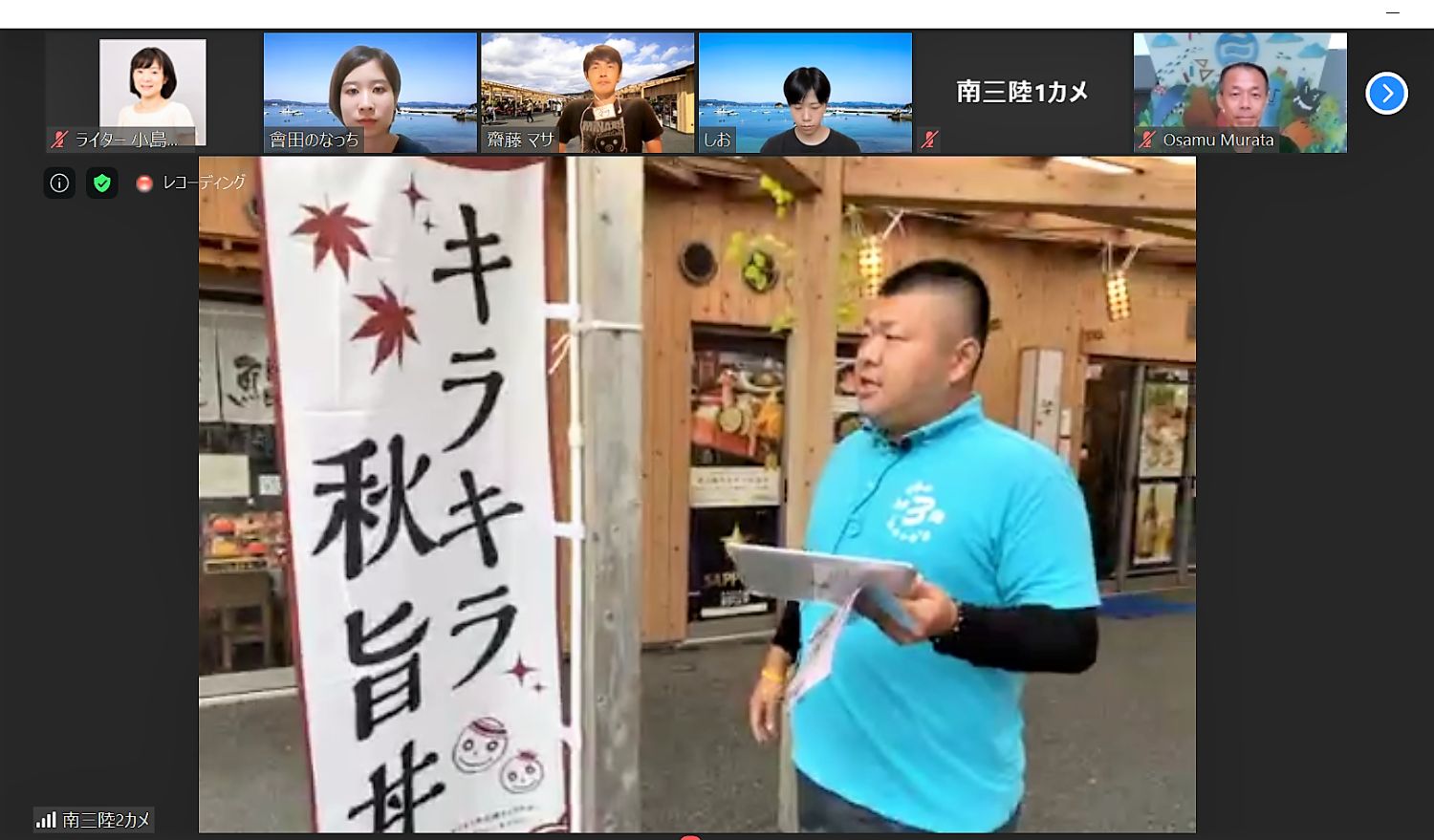 青いポロシャツを着た佐藤潤也さんが、飲食店前の「」キラキラ秋旨丼」と書かれたのぼり旗を見ながら話している様子のオンラインツアーの画面の写真
